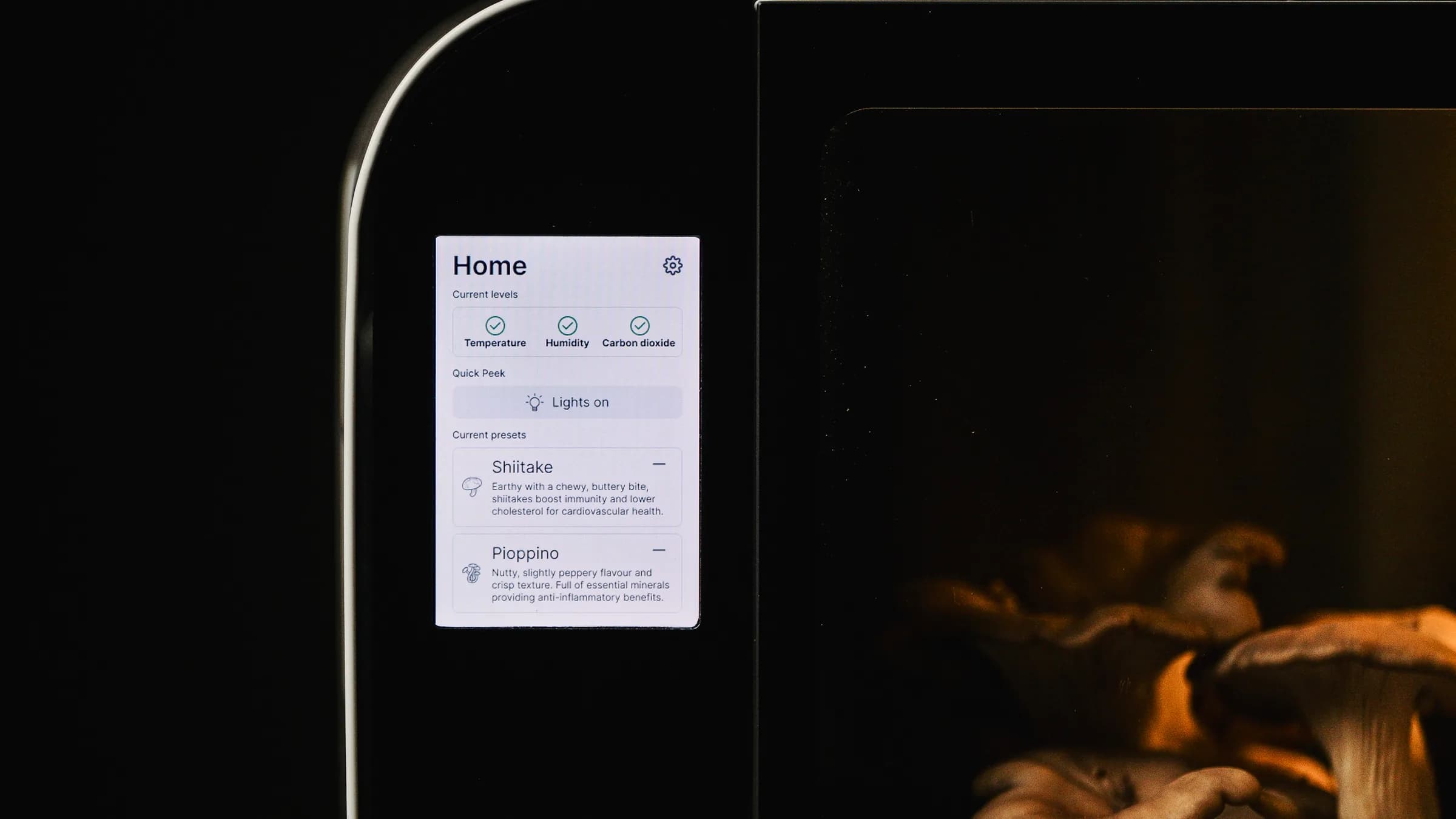 The Flush cabinet in a dark room, its touchscreen lit and mushrooms growing inside