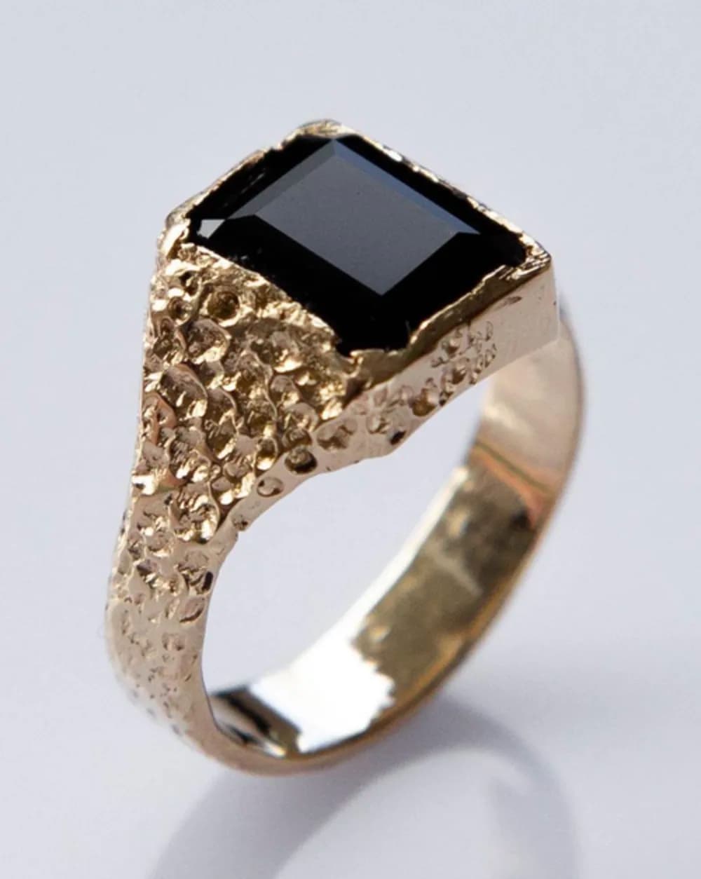 A black stone set in a textured silver ring
