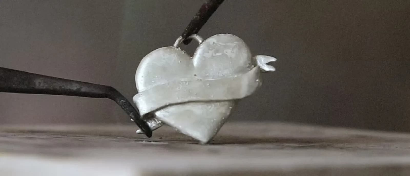 Hands forming a Loyal Heart pendant at a jewellery bench